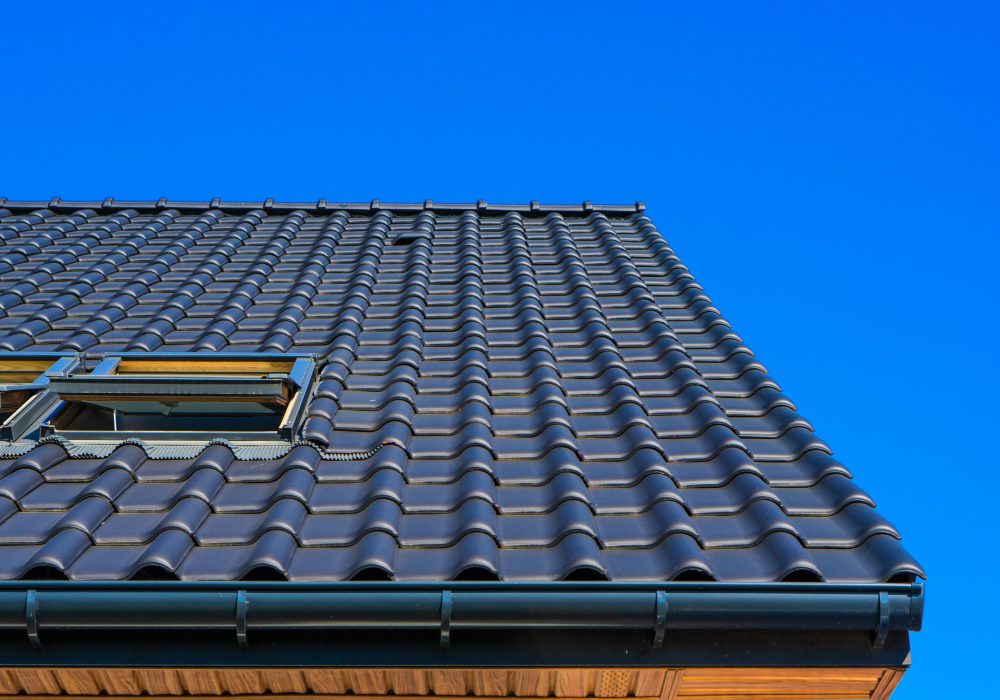 A vertical low angle closeup shot of the black roof of a building with a blue background